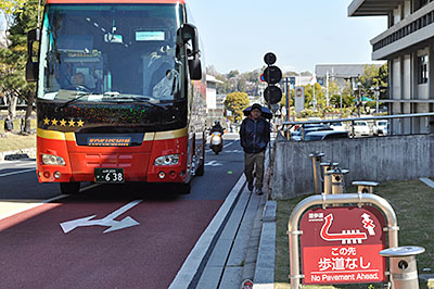 バスターミナル開業の日、奈良市道の車道路肩を歩く通行者をよけて走行する観光バス＝2019年4月13日、同市登大路町