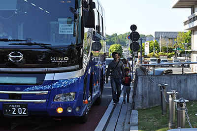 信号待ちで停止した観光バスの脇を歩く通行者＝2019年5月4日、奈良市登大路町