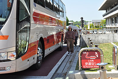 信号待ちで停止した観光バスの脇を歩く通行者＝2019年5月4日、奈良市登大路町
