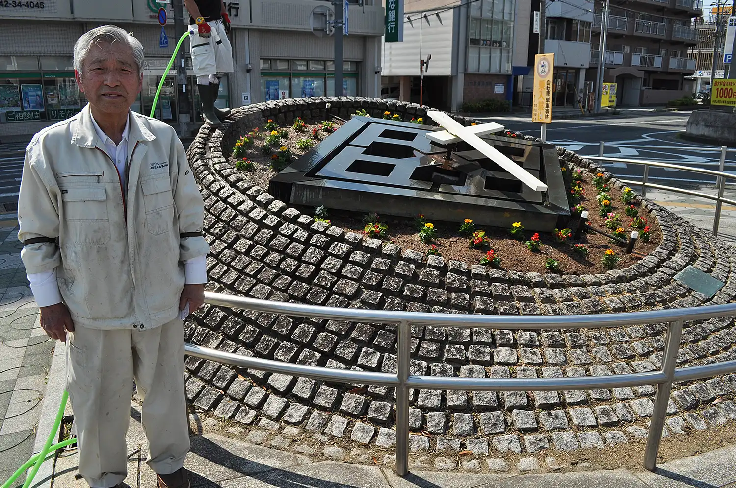 花時計に修理した針を取り付ける上田技研産業の上田全宏会長＝2025年5月14日、奈良県大和郡山市高田町のJR郡山駅西側広場、浅野善一撮影