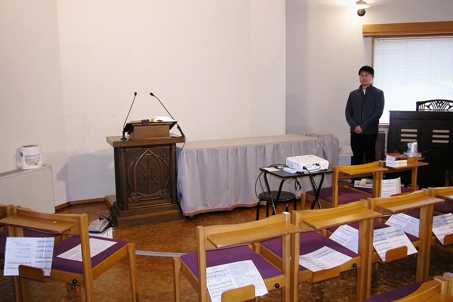 礼拝堂にある講壇(左)と牧師の藤川さん=2026年2月21日、奈良市高畑町の奈良高畑教会、浅野詠子撮影